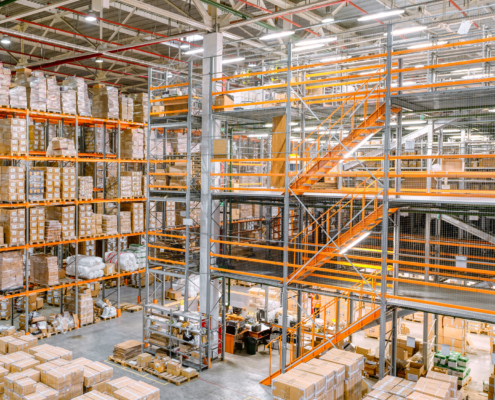Large industrial warehouse. Tall racks are completely filled with boxes and containers